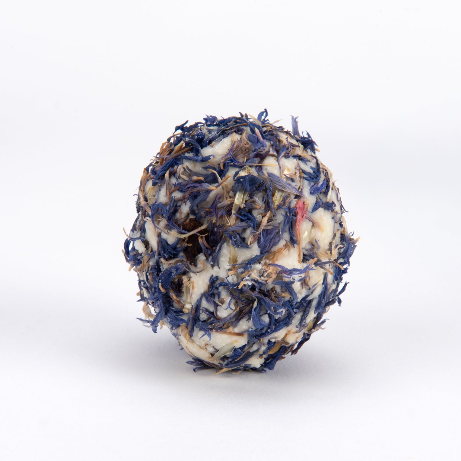 A spherical herbal tea or herbal supplement ball made of dried blue flowers, white wax, and brown herbal ingredients, centered on a clean white background.