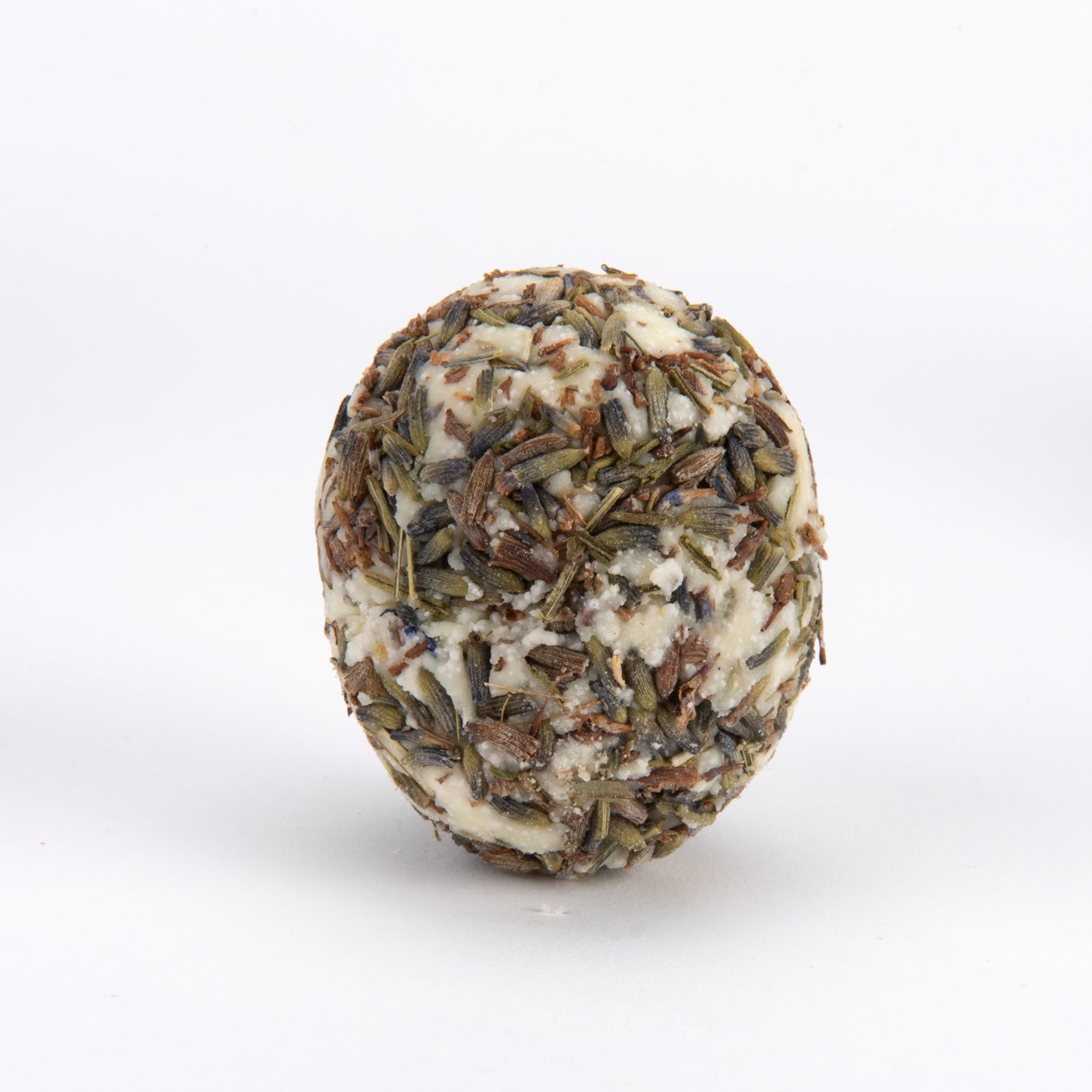 A round, textured handmade soap bar featuring a blend of off-white wax and dried lavender buds, photographed on a seamless white background.