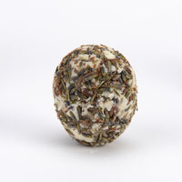 A round, textured handmade soap bar featuring a blend of off-white wax and dried lavender buds, photographed on a seamless white background.