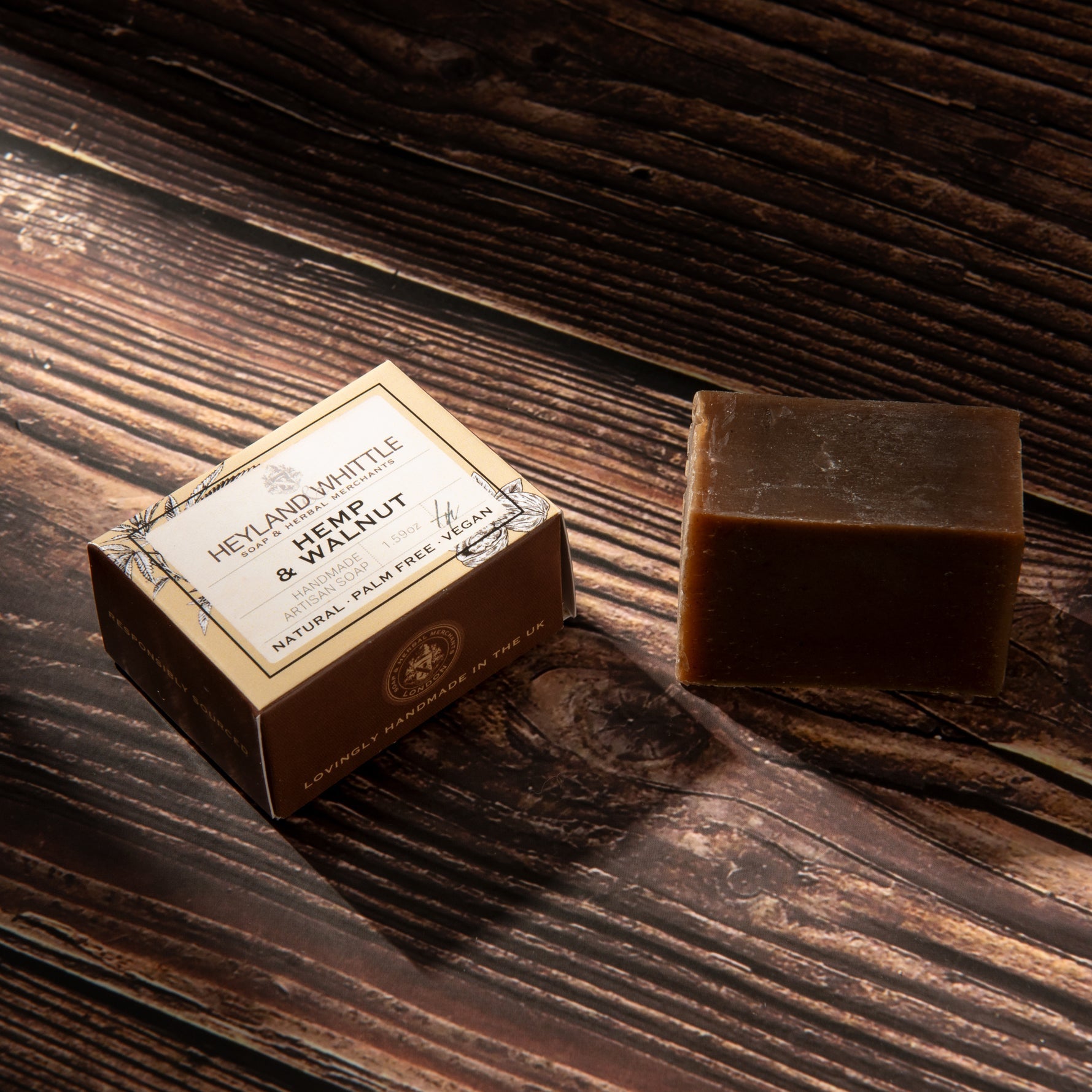 A bar of soap and its box on a dark wooden surface. 