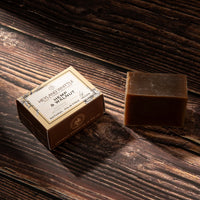 A bar of soap and its box on a dark wooden surface. 