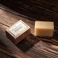 A rectangular bar of pale beige soap stands beside a small brown paper box labeled 